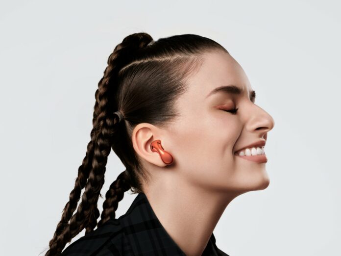 HUAWEI FreeBuds 5 -Character_orange_white background_close-up_woman_Panorama (Custom) HUAWEI FreeBuds 5