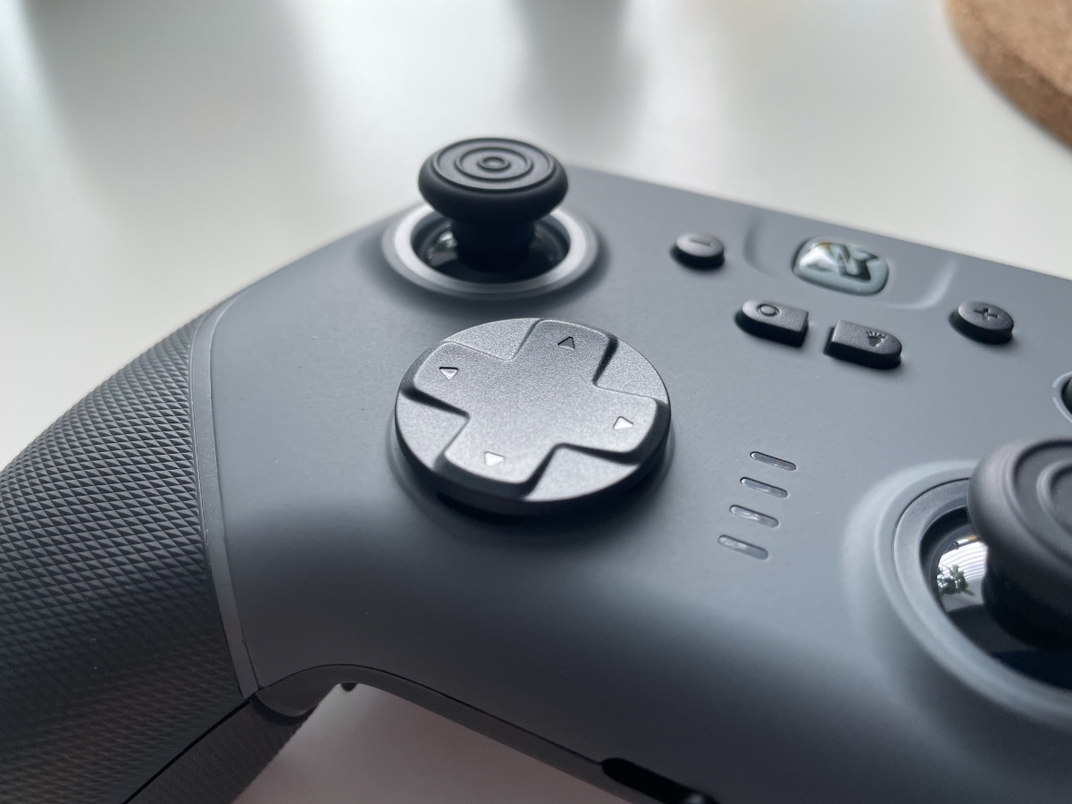 A black gaming controller with various buttons and joysticks on a white background.