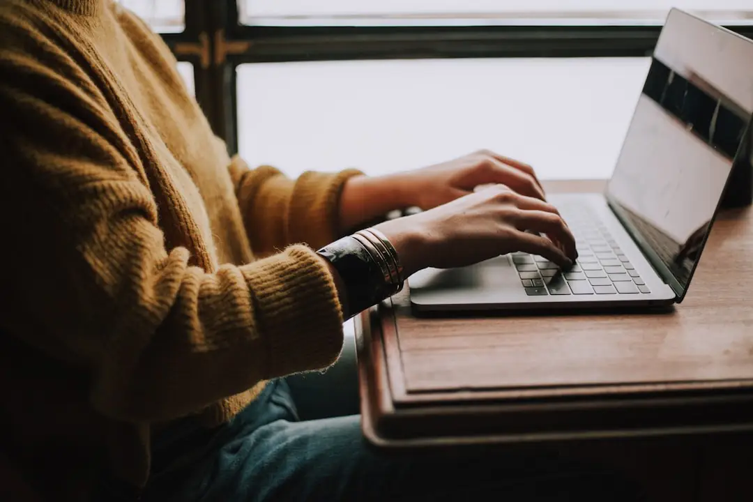 A person focused on typing on a laptop, utilizing account planning software for effective project management.