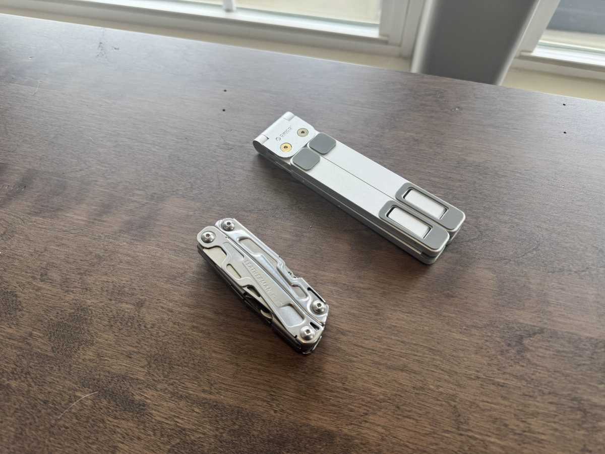 Folded ORICO PN-1 stand next to a compact multitool