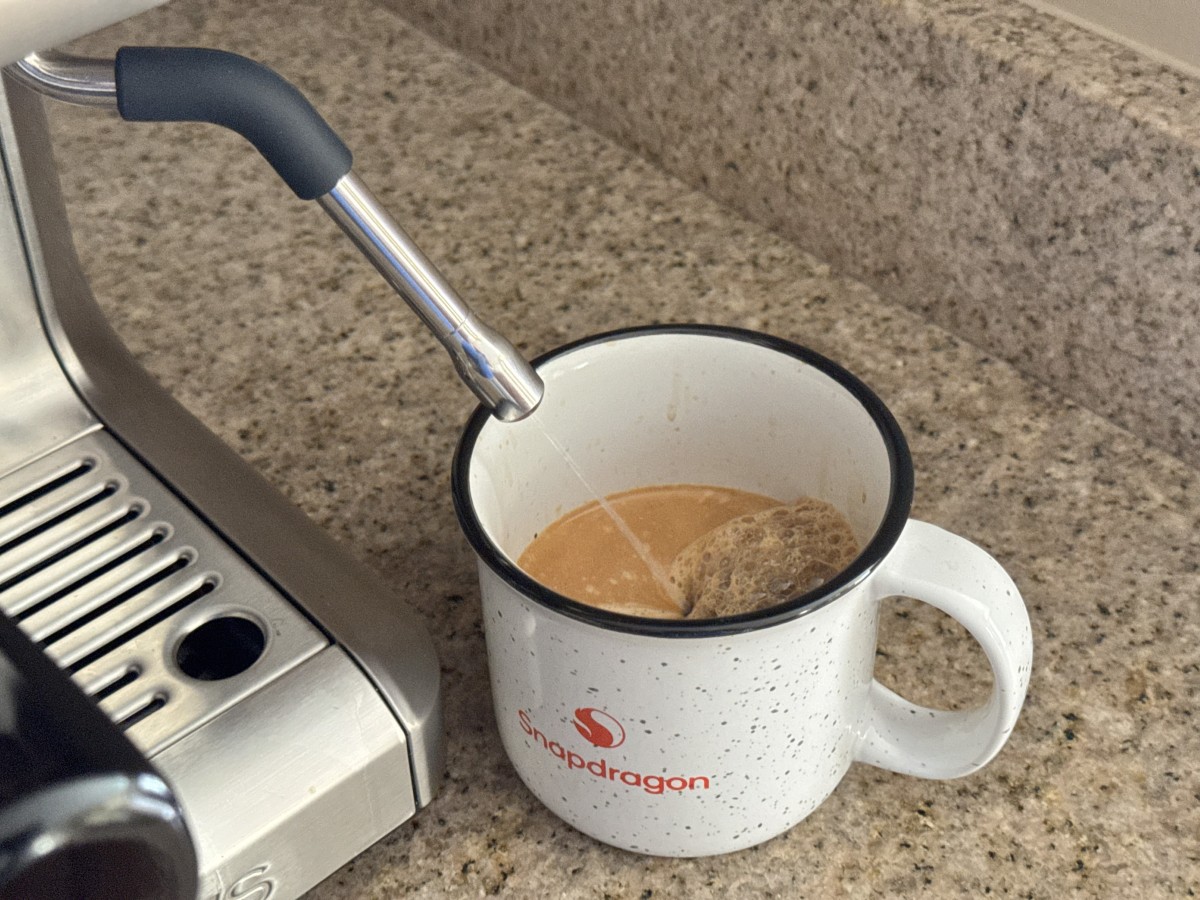 Steam wand dispensing hot water into a ceramic mug Steam wand dispensing hot water into a ceramic mug