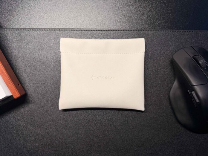 White ATK Gear carrying pouch placed on a desk beside a keyboard and mouse. White ATK Gear carrying pouch placed on a desk beside a keyboard and mouse.
