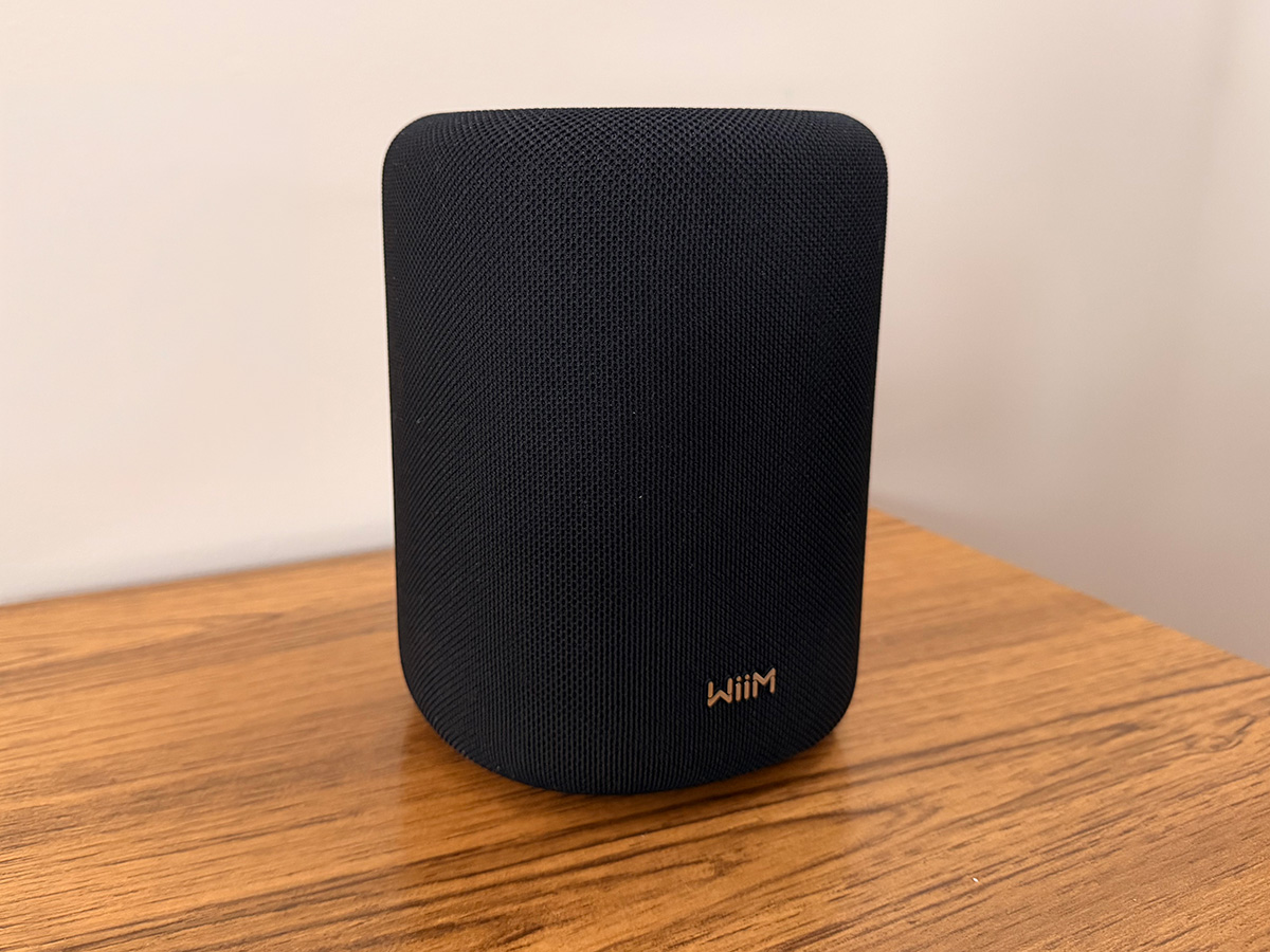 Front view of the black WiiM Sound Lite wireless speaker on a wooden table Front view of the black WiiM Sound Lite wireless speaker on a wooden table