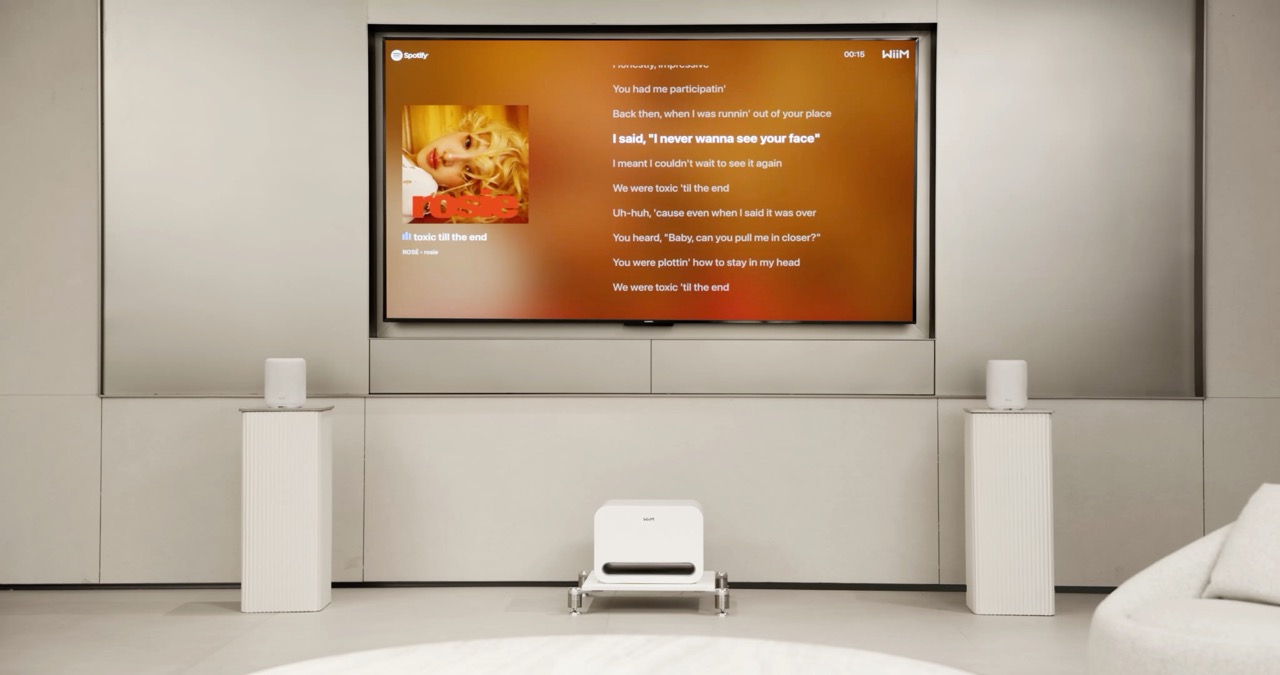 Two WiiM Sound Lite speakers paired in stereo with a WiiM Sub Pro, demonstrating a complete wireless home audio system with Spotify lyrics displayed on a TV. Two WiiM Sound Lite speakers paired in stereo with a WiiM Sub Pro, demonstrating a complete wireless home audio system with Spotify lyrics displayed on a TV.