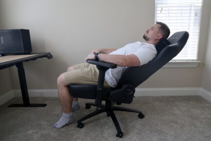 Side view of the DXRacer Martian Pro XL gaming chair with a person demonstrating its electric reclining backrest